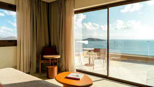 Moderni hotellihuone suurilla lasiovilla, jotka avautuvat parvekkeelle merinäköalalla. (Tekoälyn luoma teksti)
