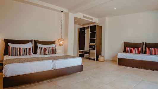 Hotellihuone, jossa suuri sänky, koristeellisia tyynyjä ja avoin vaatekaappi. (Tekoälyn luoma teksti)