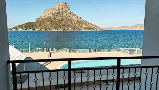 Kuvassa näkyy parvekkeen näkymä uima-altaalle ja merelle, taustalla vuorinen saari. (Tekoälyn luoma teksti)