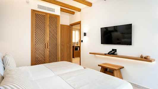 Hotellihuoneen kuva, jossa kaksi erillistä vuodetta, puuyksityiskohtia ja seinälle asennettu televisio. (Tekoälyn luoma teksti)