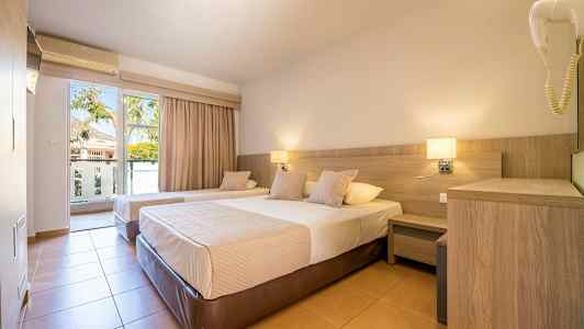 Hotellihuone, jossa kaksi yhden hengen vuodetta, yöpöytä ja parvekeovi näkymällä. (Tekoälyn luoma teksti)