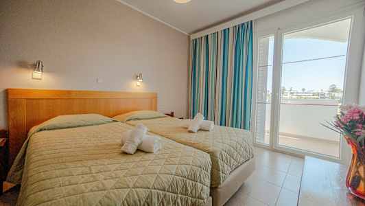 Hotellihuone, jossa kaksi erillistä vuodetta, ikkuna ja koristeita. (Tekoälyn luoma teksti)