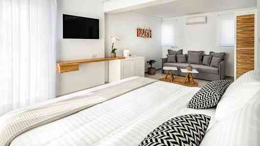 Valoisa, nykyaikainen hotellihuone, jossa on sänky, sohva ja televisio. (Tekoälyn luoma teksti)