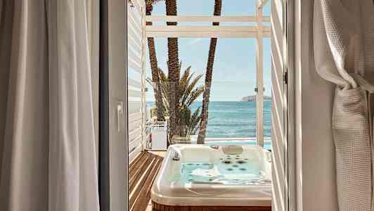 Näkymä huoneesta terassille, jossa on poreallas, palmuja ja meri. (Tekoälyn luoma teksti)