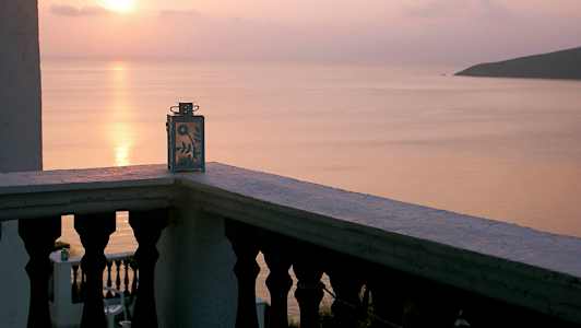 Näkymä parvekkeelta koristeellinen kynttilälyhty, auringonlasku meren yllä. (Tekoälyn luoma teksti)