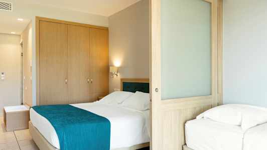 Hotellihuone, jossa parivuode ja yhden hengen vuode sekä puinen liukuovi. (Tekoälyn luoma teksti)