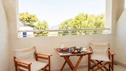 Kaksi tuolia ja pöytä, jolla on aamupalaa parvekkeella näkymä puihin. (Tekoälyn luoma teksti)