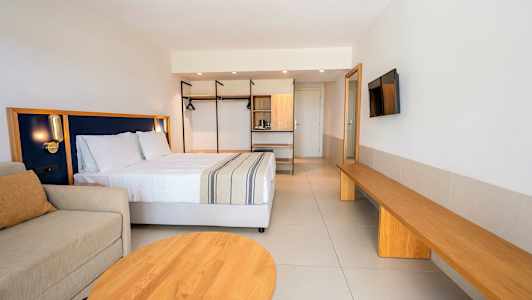 Nykyaikainen hotellihuone, jossa on parivuode, sohva ja puiset sisustusmateriaalit. (Tekoälyn luoma teksti)