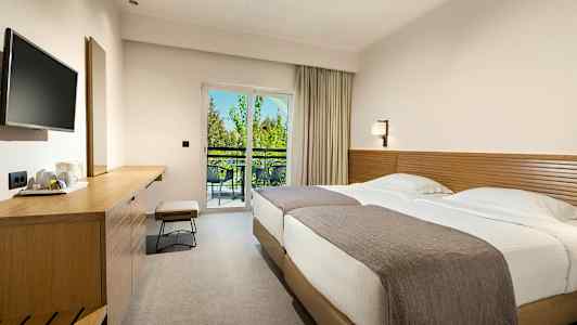 Hotellihuone, jossa kaksi sänkyä, työpöytä ja parveke näkymällä. (Tekoälyn luoma teksti)