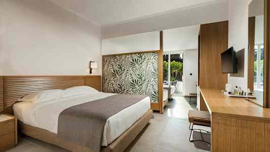 Hotellihuone, jossa on sänky, puinen pöytä ja moderni sisustus. (Tekoälyn luoma teksti)