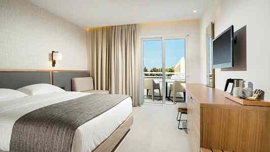 Moderni hotellihuone, jossa on parivuode, istuinalue ja kalustettu parveke. (Tekoälyn luoma teksti)