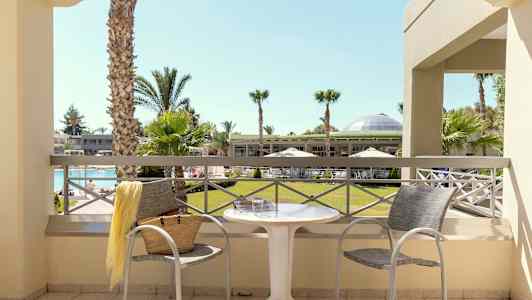 Näkymä parvekkeelta puutarhaan, jossa palmuja ja uima-allas. (Tekoälyn luoma teksti)