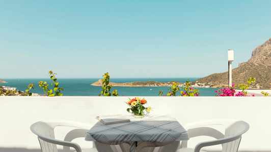 Näkymä merelle parvekkeelta, jossa on pöytä, kaksi tuolia ja kukkavaasi. (Tekoälyn luoma teksti)