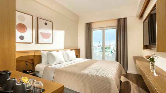 Hotellihuone, jossa on parisänky, moderni sisustus ja ikkunat näkymällä kaupunkiin. (Tekoälyn luoma teksti)