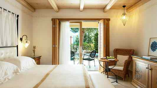 Makuuhuone, jossa parivuode, vaaleita huonekaluja ja lasiovet, jotka johtavat kalustetulle ulkoterassille. (Tekoälyn luoma teksti)