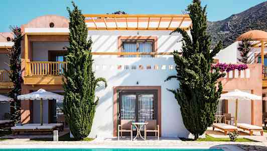 Kuva rakennuksesta, jossa on terassi ja parveke, ympäröitynä vihreillä puilla ja uima-allas etualalla. (Tekoälyn luoma teksti)