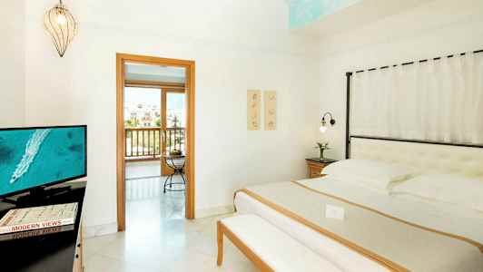 Hotellihuoneen sisustus, jossa on sänky, televisio ja aukko parvekkeelle. (Tekoälyn luoma teksti)