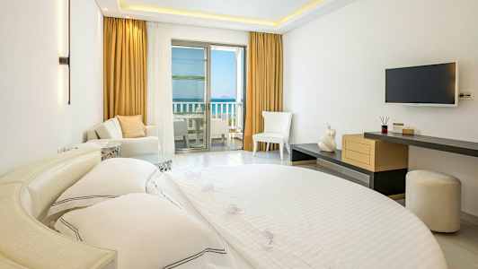 Hotellihuoneen sisustus, jossa sänky, istumapaikkoja ja parveke merinäköalalla. (Tekoälyn luoma teksti)