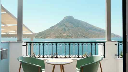 Kaksi tuolia ja pöytä parvekkeella, josta on näkymä merelle ja vuorelle. (Tekoälyn luoma teksti)