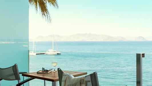 Näkymä merelle parvekkeelta, jossa on pöytä ja tuolit. (Tekoälyn luoma teksti)