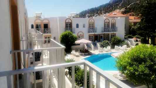 Hotellialue, jossa on uima-allas ja aurinkotuoleja vihreiden kasvien ympäröimänä. (Tekoälyn luoma teksti)