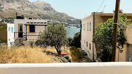 Näkymä taloista ja ulkoterasseista, taustalla vuoret ja meri. (Tekoälyn luoma teksti)