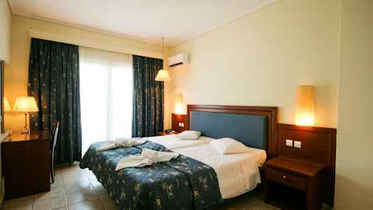 Kuva hotellihuoneesta, jossa on parivuode, kirjoituspöytä ja yöpöytä. (Tekoälyn luoma teksti)