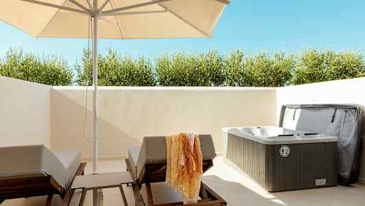 Ulkoalue, jossa aurinkotuoleja, varjo ja poreallas. (Tekoälyn luoma teksti)