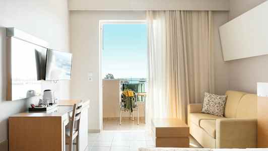 Hotellihuone, jossa parveke, televisio, kirjoituspöytä, sohva ja sänky. (Tekoälyn luoma teksti)