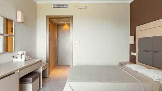 Hotellihuone, jossa on parivuode, kirjoituspöytä tuolin ja peilin kanssa sekä ovi muihin tiloihin. (Tekoälyn luoma teksti)