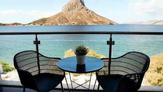 Näkymä merelle parvekkeelta, jossa on kaksi tuolia ja pöytä. (Tekoälyn luoma teksti)