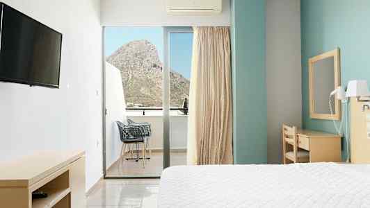 Hotellihuone, jossa on sänky, kirjoituspöytä ja parveke, josta on näkymä vuorelle. (Tekoälyn luoma teksti)