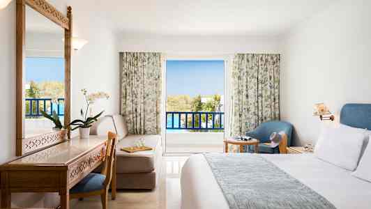 Hotellihuone, jossa parveke ja huonekalut, kuten sänky, kirjoituspöytä, tuoli ja nojatuoli. (Tekoälyn luoma teksti)