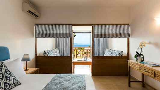 Hotellihuone, jossa on parivuode, yöpöytiä ja merinäköala parvekkeelta. (Tekoälyn luoma teksti)