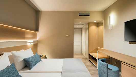 Moderni hotellihuone, jossa on parivuode, työpöytä ja televisio. (Tekoälyn luoma teksti)