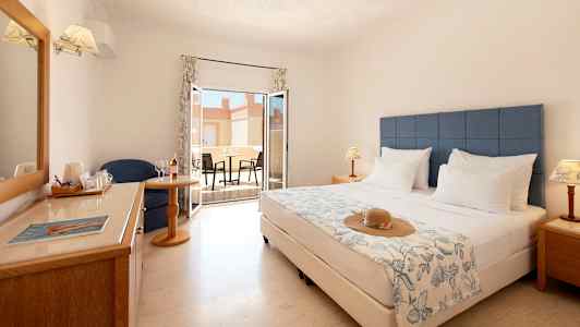 Hotellihuone, jossa parivuode, istuinryhmä, ikkuna ja sisustettu terassi. (Tekoälyn luoma teksti)