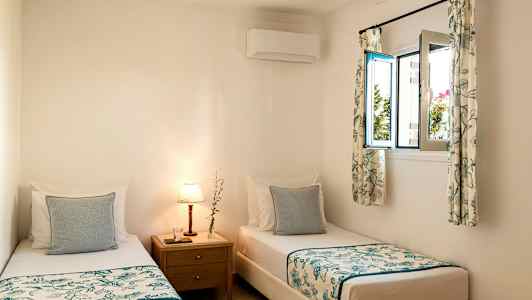 Huoneessa kaksi erillistä vuodetta ja yöpöytä, jossa lamppu. (Tekoälyn luoma teksti)