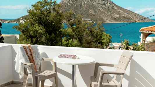 Näkymä terassilta, jossa on kaksi tuolia ja pöytä, merelle ja taustalla olevaan kallioon. (Tekoälyn luoma teksti)