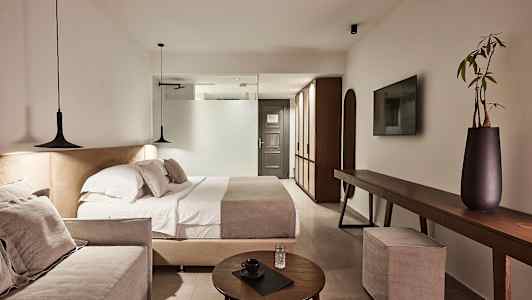 Moderni hotellihuone, jossa parivuode, sohva ja tyylikäs sisustus. (Tekoälyn luoma teksti)