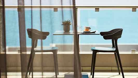 Pöytä ja kaksi tuolia parvekkeella merinäköalalla. (Tekoälyn luoma teksti)