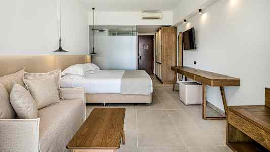 Hotellihuone, jossa on sänky, sohva ja puukalusteet. (Tekoälyn luoma teksti)