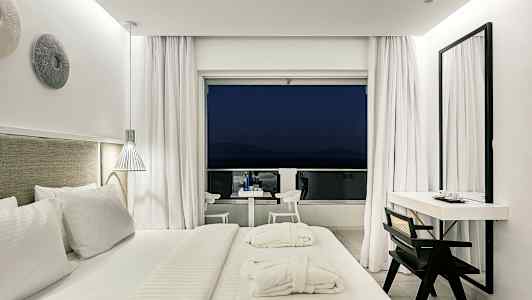 Moderni hotellihuone, jossa suuri sänky ja pääsy parvekkeelle. (Tekoälyn luoma teksti)