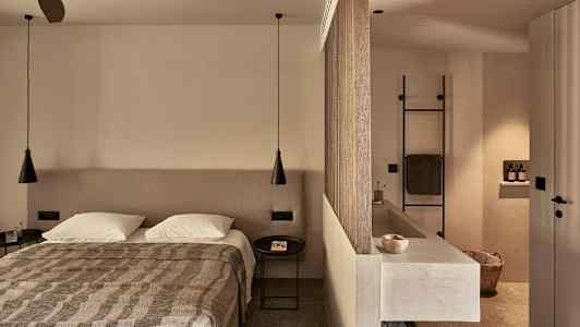 Makuuhuone, jossa on parivuode, jakaja erottamassa kylpyhuoneen pesualtaineen ja pyyhetelineineen. (Tekoälyn luoma teksti)