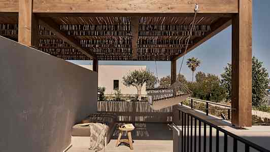 Ulkoiluterassi, jossa on puinen pergola, riippumatto ja istuma-alue, jossa on pöytä. (Tekoälyn luoma teksti)