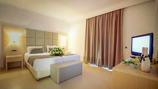 Hotellihuone, jossa on parivuode ja kukkakoriste. (Tekoälyn luoma teksti)