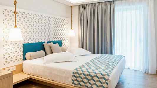 Hotellihuone, jossa on parivuode, tyylikäs sisustus ja vaaleat verhot. (Tekoälyn luoma teksti)