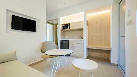 Moderni hotellihuone, jossa pieni oleskelutila ja keittokomero. (Tekoälyn luoma teksti)