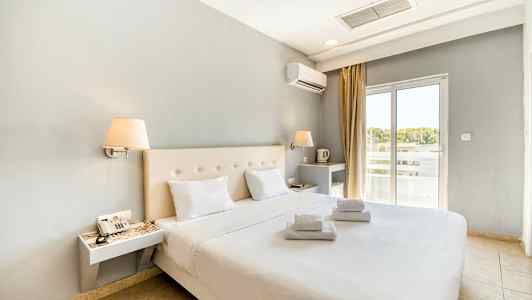 Modernisti sisustettu hotellihuone, jossa parivuode ja valkoiset lakanat. Ikkuna tuo valoa. (Tekoälyn luoma teksti)