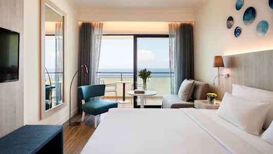 Hotellihuone, jossa merinäköala, sohva, istuinalue ja sänky. (Tekoälyn luoma teksti)