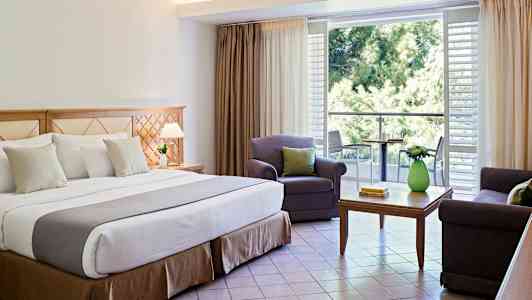 Hotellihuoneen sisustus, jossa on parivuode, istuinalue ja parveke. (Tekoälyn luoma teksti)